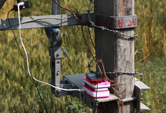 Mobile phones being charged by tapping wires from electricity poles